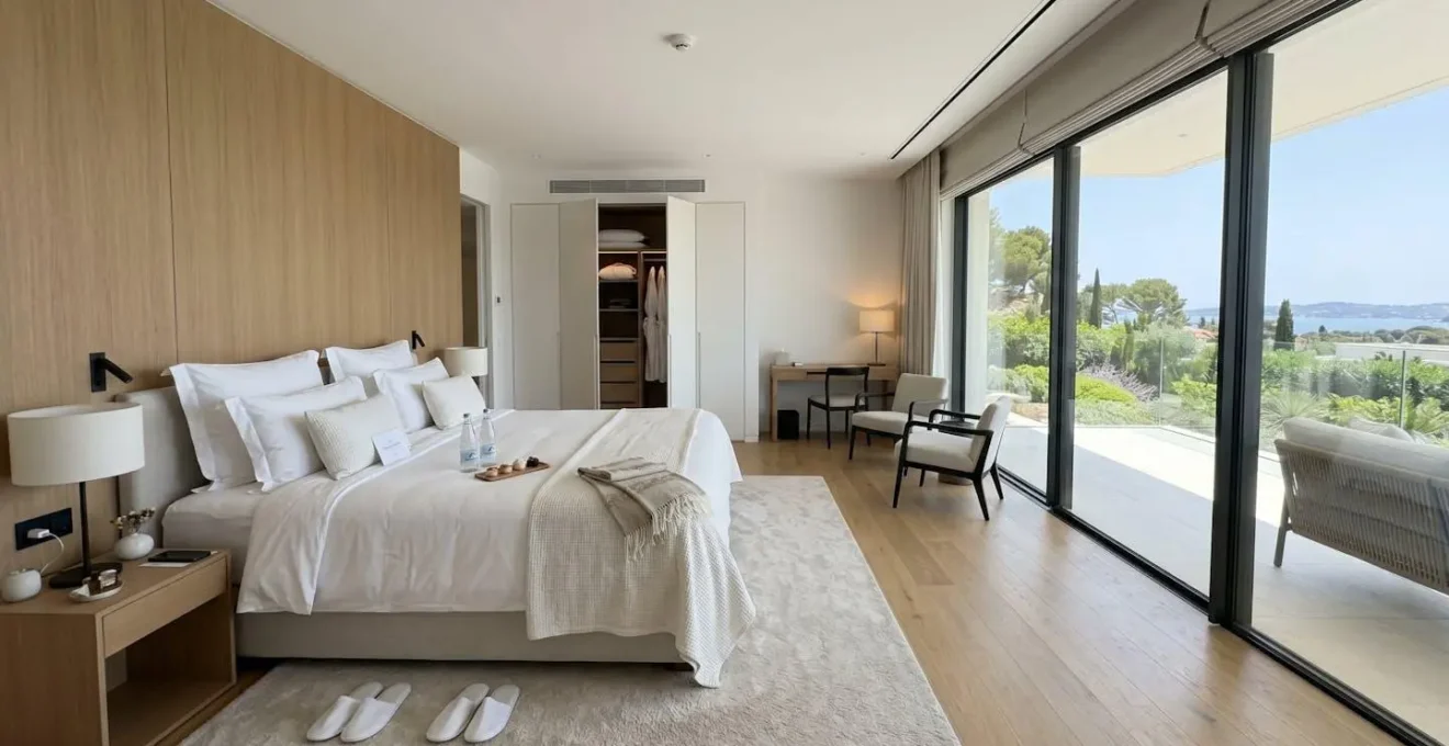 Immaculate contemporary villa bedroom with crisp white linens and soft evening light through large windows